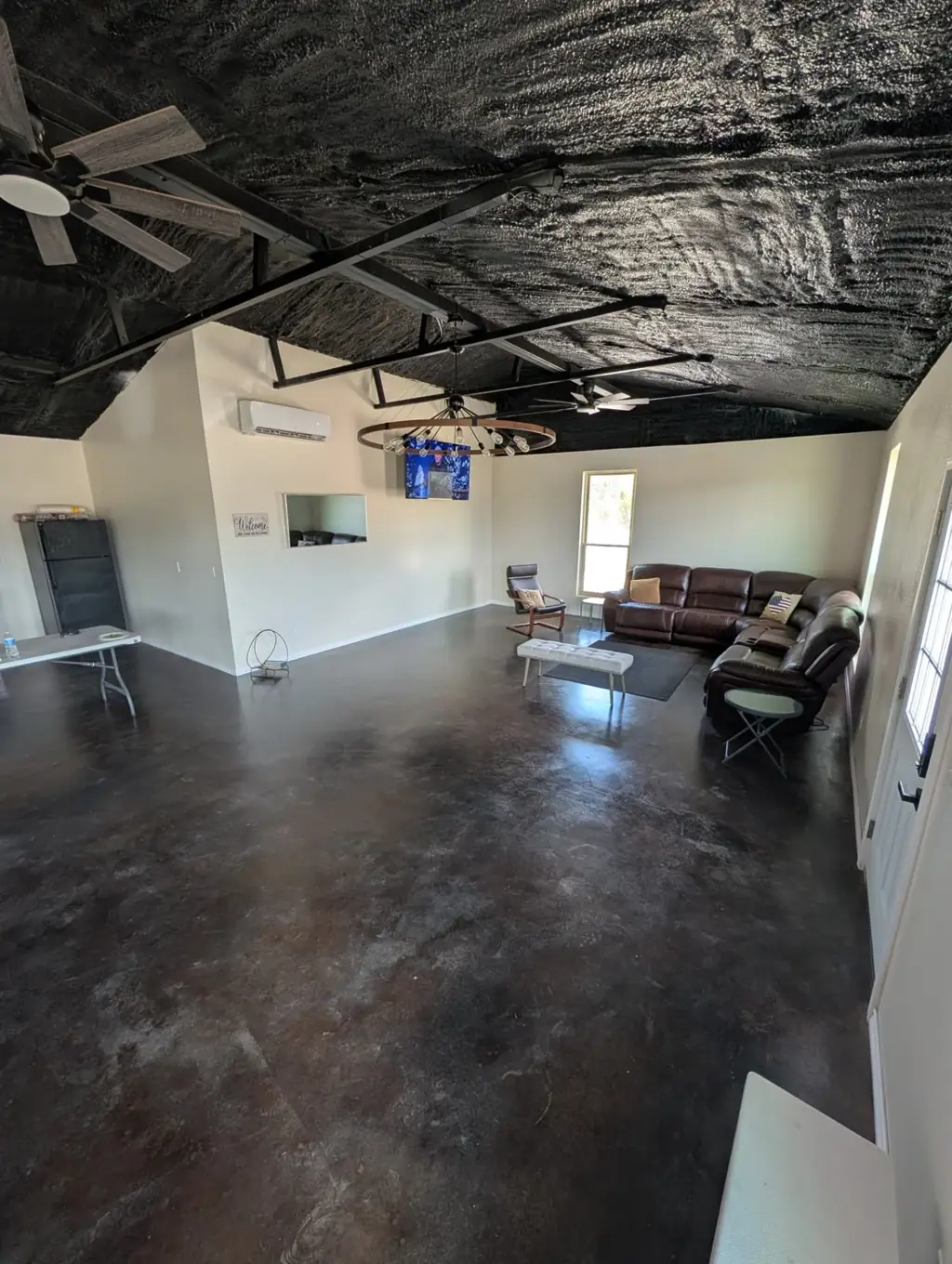 Open gathering hall in the event space at Journey's RV Park in Temple, Texas, with recliner sofas, ceiling fans, and polished concrete floors