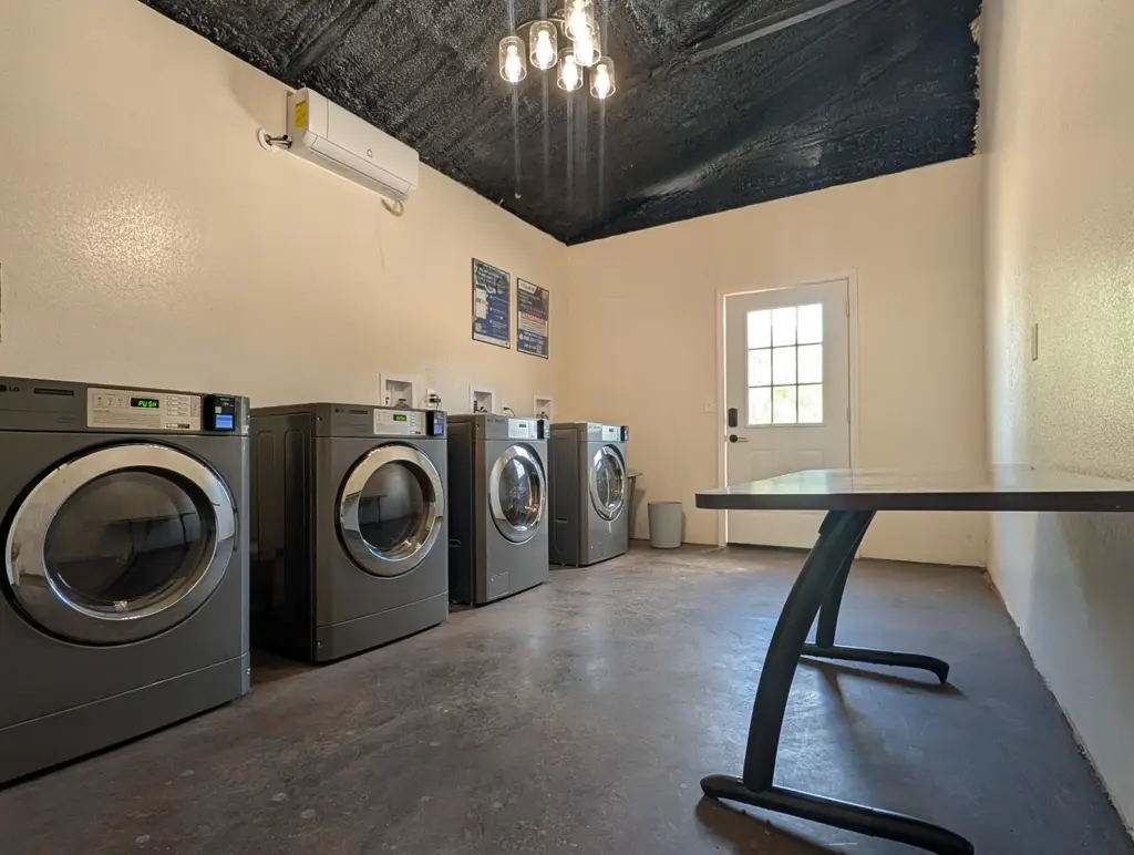Laundry room at Journey's RV Park with commercial washers and dryers, folding table, and air conditioning